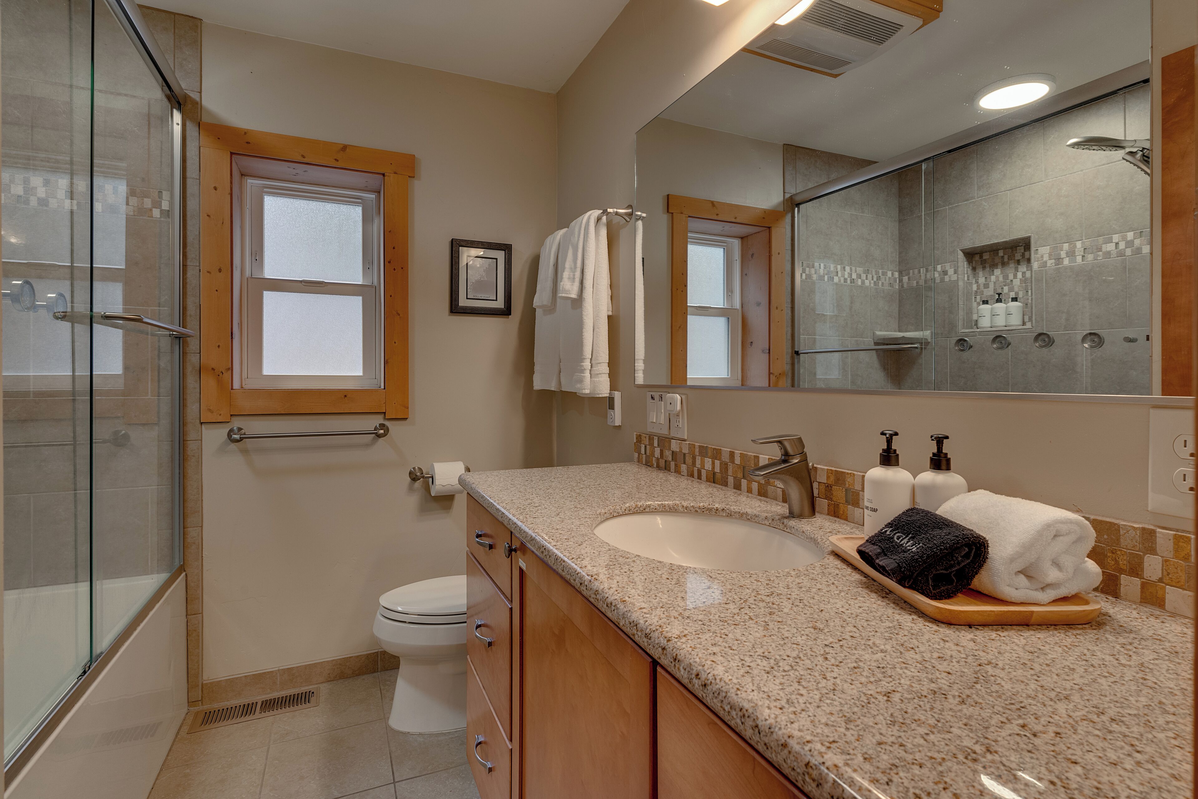 Une salle de bain avec une douche à parois de verre, un lavabo avec un meuble-vasque et un grand miroir.