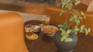 A cozy room with a stone fireplace, a wooden table with snacks and drinks, and comfortable seating.