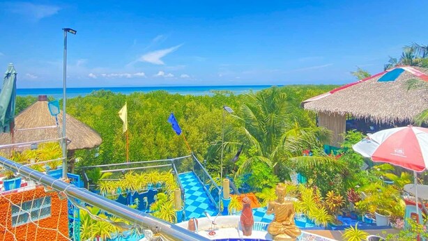 A resort with a thatched-roof structure, a Buddha statue, and a view of the ocean. - Pirate Galeon (Carcar)