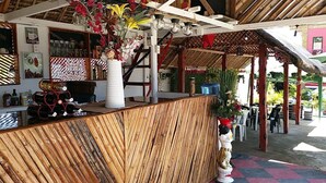 A wooden bar area with a counter, a white vase with flowers, and a red and white checkered floor. - Pirate Galeon (Carcar)