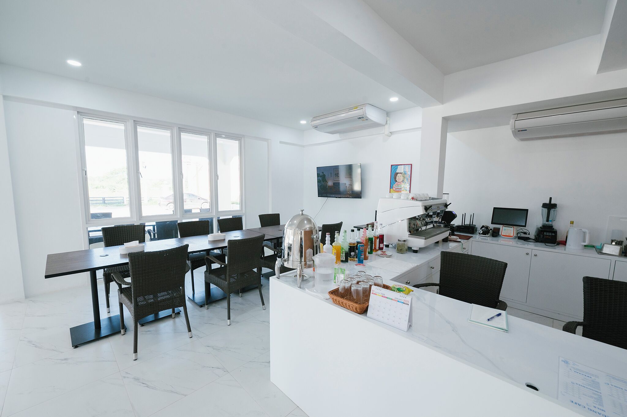 Una cocina moderna con una isla central, un comedor con una mesa larga y sillas, y un ventanal que proporciona luz natural.
