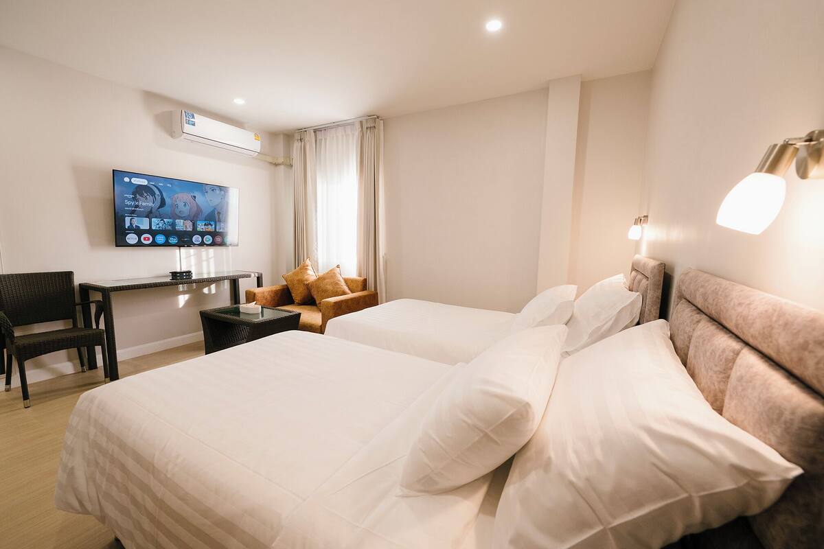A hotel room with a bed, a desk, a chair, a TV, and a lamp.