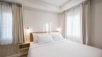 A hotel room with a large bed, two bedside tables, and curtains on the windows.
