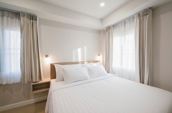 A hotel room with a large bed, two bedside tables, and curtains on the windows. - Eng Fah Luang Hotel (Chiang Rai)