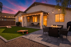 A patio with a fire pit, outdoor seating, and string lights.