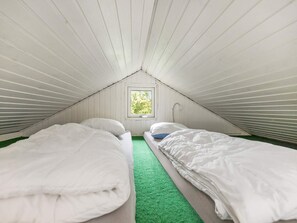 A small attic bedroom with two beds, a window, and a green carpet. - 6 Person Holiday Park Home in Vipperod (Vipperod)