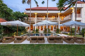 A hotel with a pool, lounge chairs, and umbrellas. - KALM Bali (Tibubeneng)