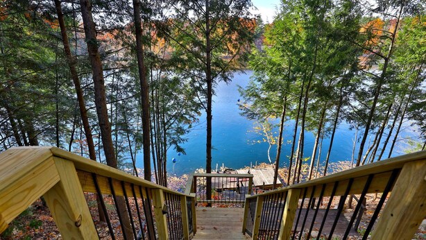 A wooden staircase leading to a dock by a lake surrounded by trees. - Lakeside Lodge at Fern Lake: 3BR/1BA Waterfront w/ Dock (Leicester)