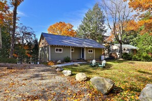 A rustic cabin with a gravel driveway and a small porch area. - Lakeside Lodge at Fern Lake: 3BR/1BA Waterfront w/ Dock (Leicester)