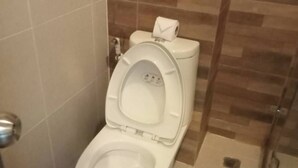 Un baño moderno con inodoro, secador de manos y dispensador de toallas de papel.