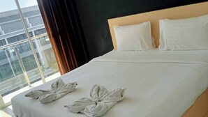 Una habitación de hotel con una cama grande, ropa de cama blanca y un mural de un pez en la pared.