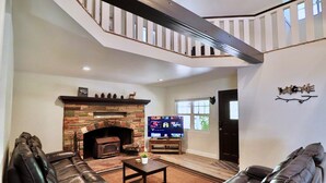 Una sala de estar con chimenea, sofás de cuero, una mesa de centro y un televisor.