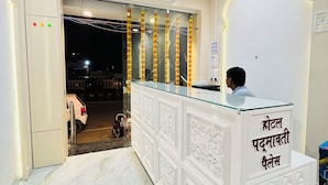 A reception desk with a sign in a non-English language, a marble floor, and an air conditioning unit above it. - Hotel Padmawati Palace (Ujjain)