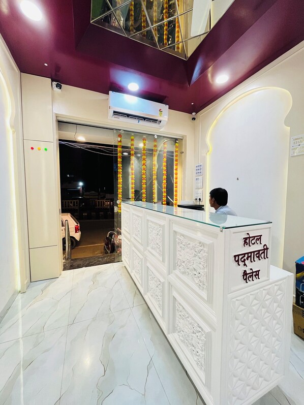 A reception desk with a sign in a non-English language, a marble floor, and an air conditioning unit above it.