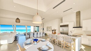 Una cocina moderna con armarios blancos, una campana extractora de acero inoxidable y una isla grande con taburetes de bar.
