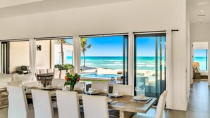 Comedor con vistas al océano, ventanas amplias y piscina.