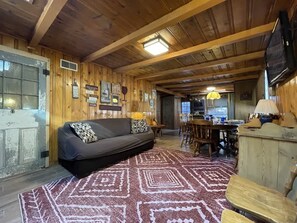 Un intérieur en bois comprenant un canapé, une table à manger, des chaises et un téléviseur.