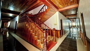 A spacious hallway with a wooden staircase leading to an upper level. - Khampaseuth Hotel (Vang Vieng)