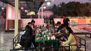 A group of people dining at an outdoor restaurant with a covered roof and tiled floor. - Khampaseuth Hotel (Vang Vieng)