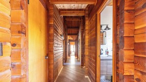 A wooden hallway with a wooden door on the left and a kitchen area visible through an open doorway.