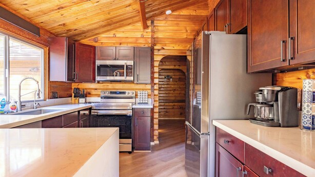 A modern kitchen with wooden cabinetry, stainless steel appliances, and a large island.