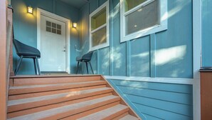 Un escalier en bois mène à une porte, devant laquelle se trouvent deux chaises.