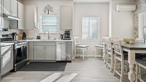 Une cuisine moderne avec des meubles blancs, un four encastré et un coin repas comprenant des chaises et une table en bois.