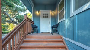 Un escalier en bois mène à une porte blanche, et deux chaises noires se trouvent sur le palier.