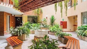 A spacious courtyard with multiple seating areas, potted plants, and a central fountain. - LOFT  1-bedroom apartment in San Borja with WiFi (San Borja)