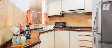 A compact kitchen with a gas stove, a built-in oven, a toaster, and a refrigerator.