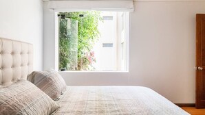 A bedroom with a large window, a tufted headboard, and a wooden door. - LOFT  1-bedroom apartment in San Borja with WiFi (San Borja)