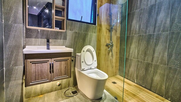A modern bathroom with a toilet, sink, and glass shower enclosure. - Dos Maya by Araw Residences (Nasugbu)