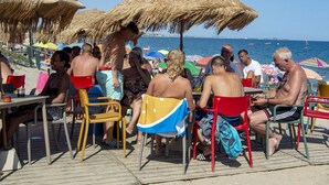 A beachside dining area with thatched umbrellas and outdoor seating. - Wooden Chalet With Parking (Mont-roig del Camp)