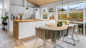 Une cuisine moderne avec des armoires blanches, un plan de travail en bois et des luminaires suspendus.