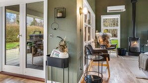 Un salon chaleureux avec une cheminée, un coin repas et une grande porte-fenêtre coulissante donnant sur un jardin.