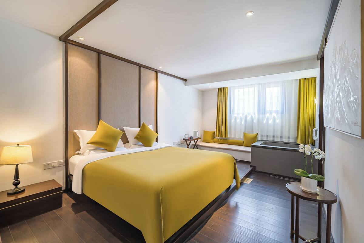 Une chambre d’hôtel avec un grand lit, une table de chevet et une fenêtre avec des rideaux.