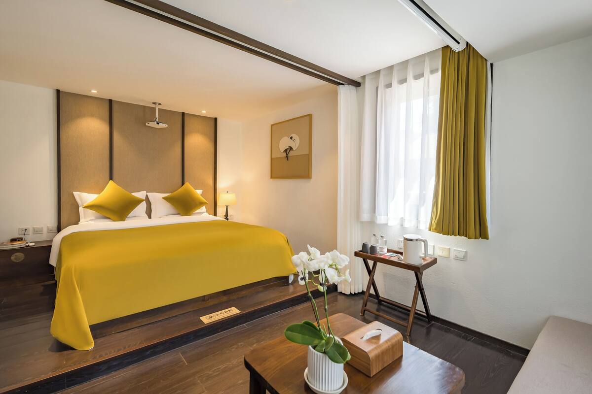 Une chambre d’hôtel avec un lit, une table de chevet, une lampe et une fenêtre avec des rideaux.