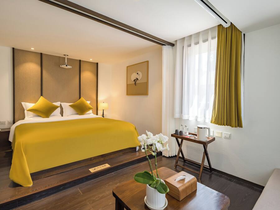 A hotel room with a bed, bedside table, lamp, and a window with curtains.
