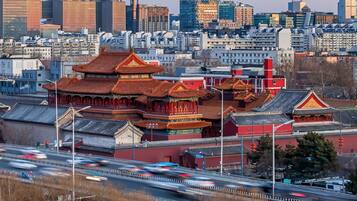 A traditional Chinese building with red and gold roofs, surrounded by modern high-rise buildings.