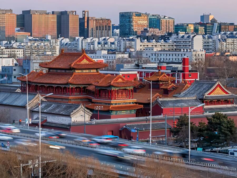 A traditional Chinese building with red and gold roofs, surrounded by modern high-rise buildings.