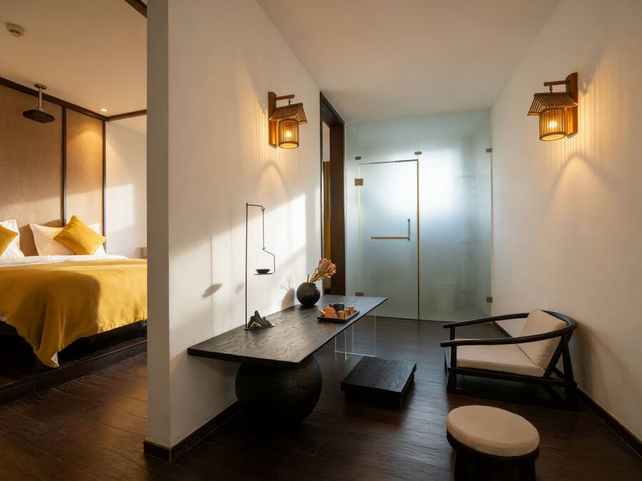 Una habitación de hotel con cama, mesita de noche, silla y escritorio con lámpara.