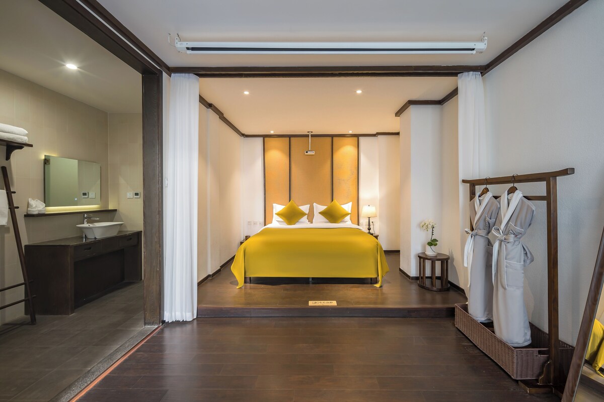 A hotel room with a bed, a bathroom with a sink, and a mirror.
