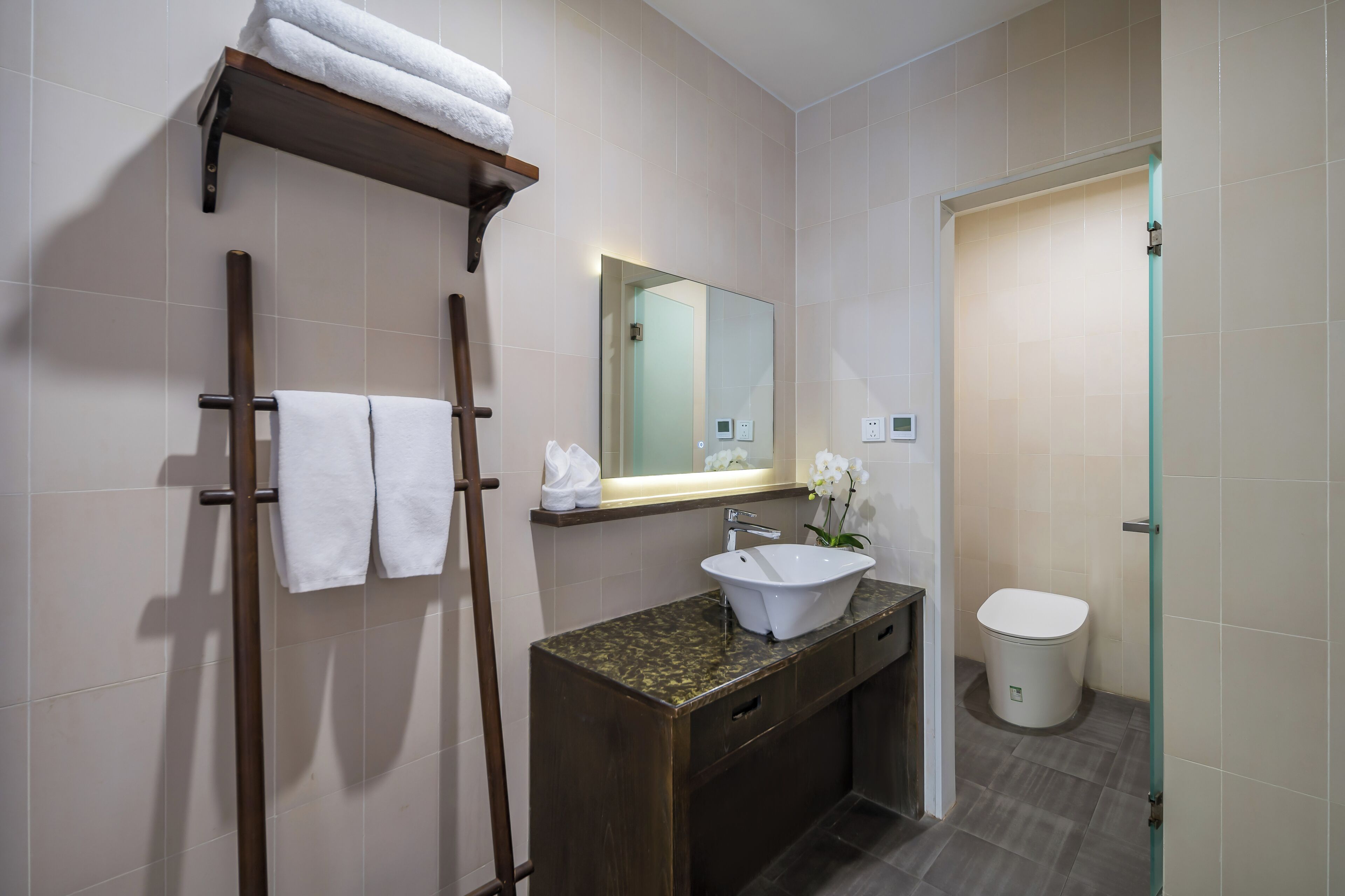 A bathroom with a wooden towel rack, a sink with a mirror, and a toilet.