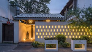 A building entrance with a tiled roof, a statue, and a wall of illuminated lights. - BEIJING DASEIN HOTEL (Beijing)
