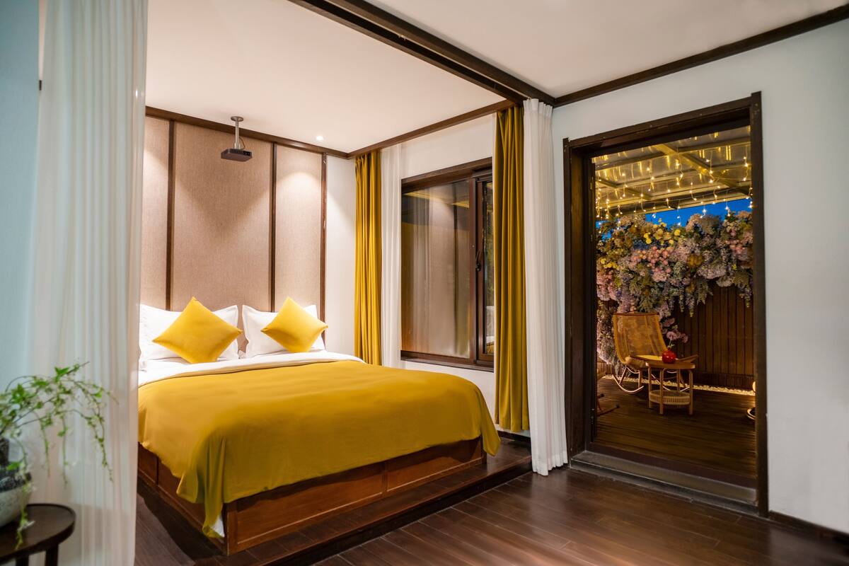 Une chambre d’hôtel avec un lit, une fenêtre, une porte donnant sur un balcon et une plante en pot.