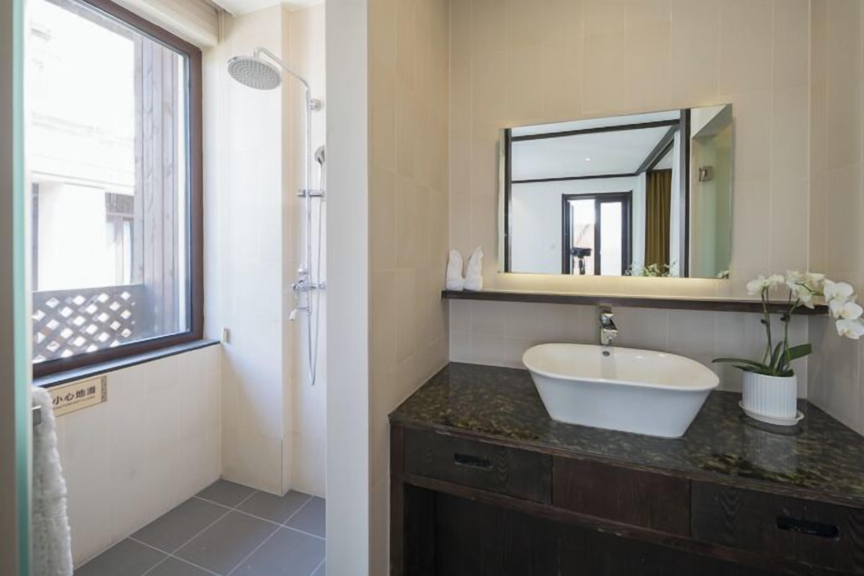 A bathroom with a sink, mirror, and shower.