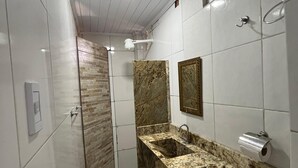 Un baño moderno con ducha, lavabo de encimera de mármol e inodoro.
