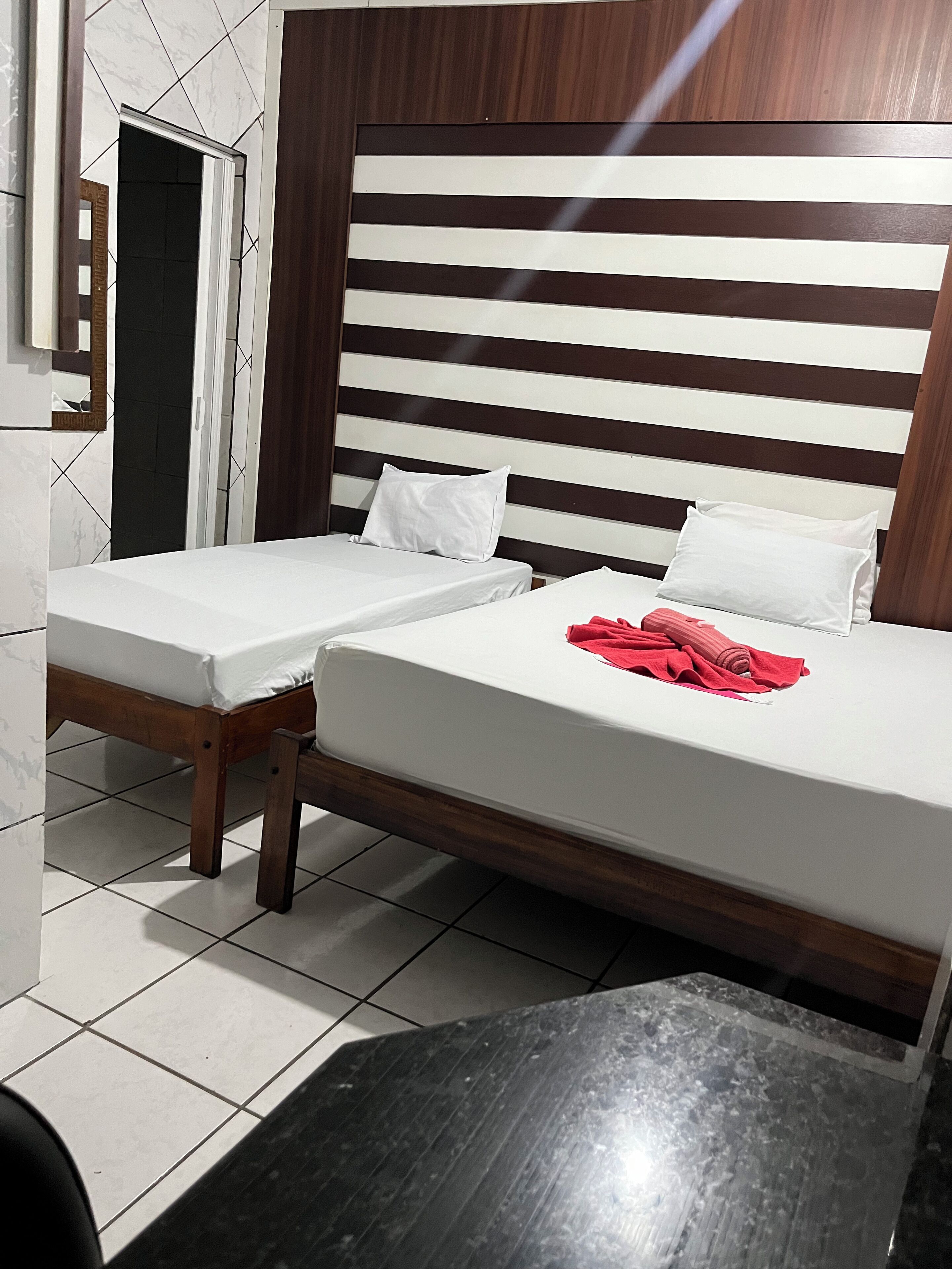 Una habitación de hotel con una cama, una mesita y un espejo.