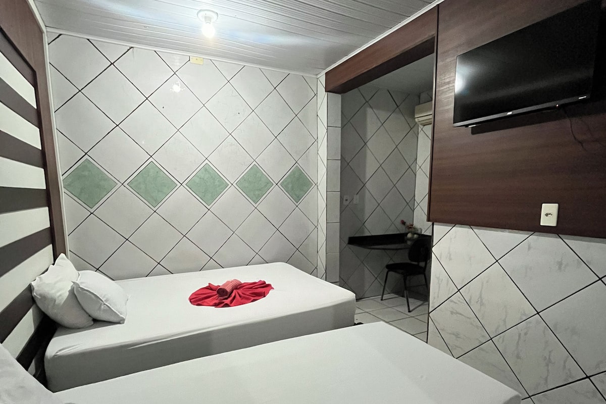Une chambre d’hôtel avec deux lits, un téléviseur fixé au mur et un bureau avec une chaise.