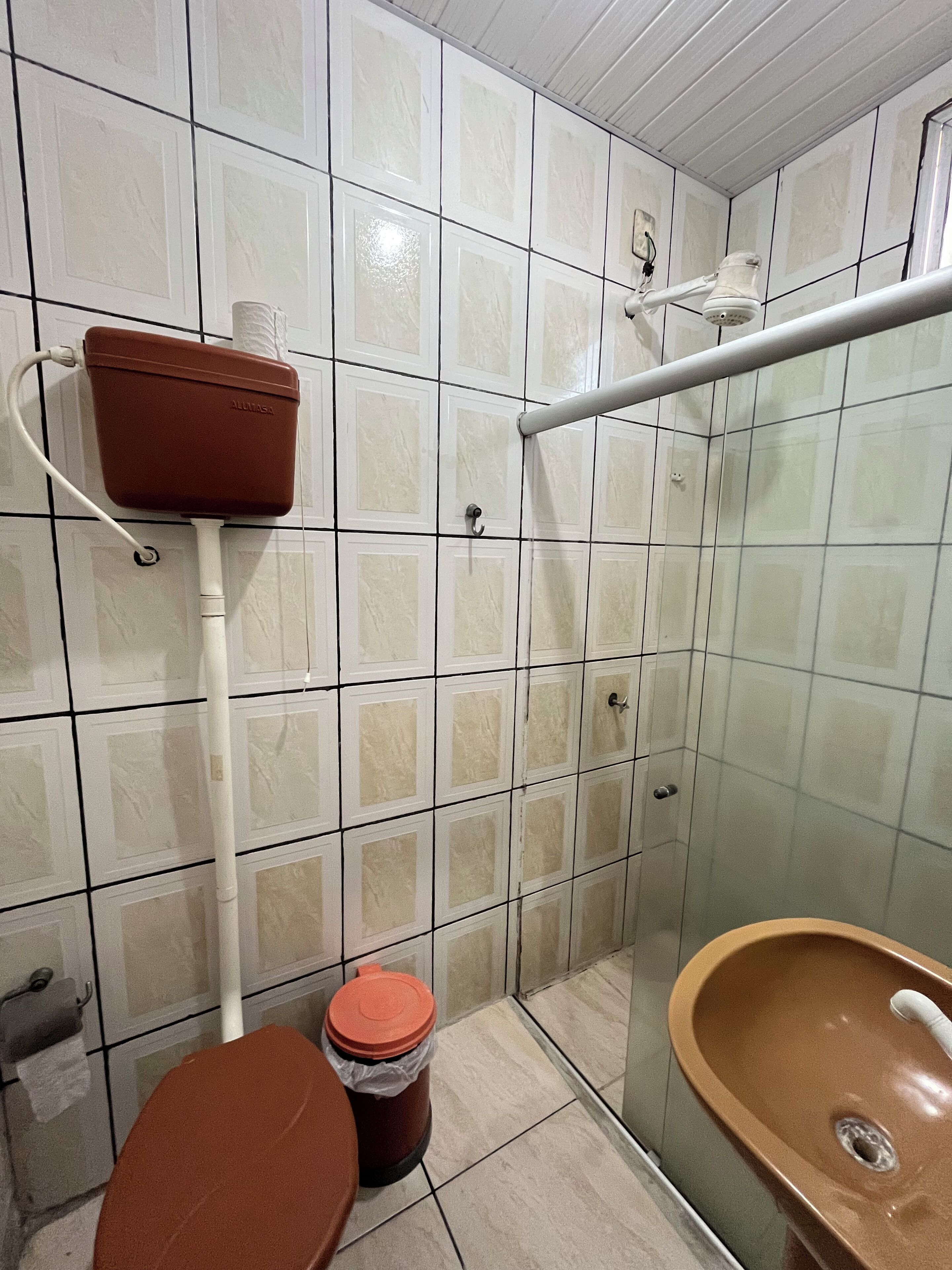 A bathroom with a toilet, a sink, a shower, and a storage unit.
